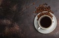 Coffee beans and coffee in a white cup on dark rusty background. Royalty Free Stock Photo