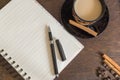 Coffee beans, cup of coffee, autumn leaves, pen and notebook on wooden deck