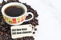 Coffee beans, a cup of coffee and label tag written with 365 NEW DAYS, 365 NEW CHANCES Royalty Free Stock Photo