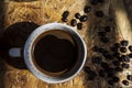 Cup of black java coffee and coffee beans on wooden background, top view