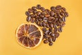 Coffee beans and dried oranges on a yellow background. Heart made of coffee beans. Love for coffee.