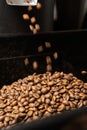 Coffee beans drop in high speed falls from roasting machine to pile of roasted bean
