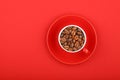 Coffee beans in espresso cup with saucer on red Royalty Free Stock Photo