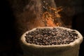 Coffee beans falling to the sack full of smoky coffee beans. Royalty Free Stock Photo