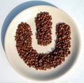 Coffee beans form an include sign on a white platter on a dark wooden background Royalty Free Stock Photo