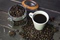 Coffee beans in glass jar with american black coffee cup on old wooden table.Creative cafe concept on rustic background Royalty Free Stock Photo