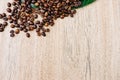 Coffee beans on a green leaf and scattered on a light wooden table, top view, closeup grains, flat lay, copy space