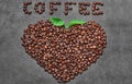 Coffee beans in heart shape with green leaves and coffee word on dark grey background Royalty Free Stock Photo