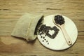 The coffee beans heart shape spilling from a burlap bag and a scoop on a textured wood surface Royalty Free Stock Photo