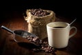 Coffee beans in metal scoop and with cup and gunny sack.