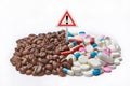 Coffee beans next to medicines and a warning exclamation mark.