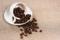 Coffee beans overflow on a white cup over a burlap sack Royalty Free Stock Photo