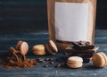Coffee beans, paper pack, macaroons and chocolate on wooden background