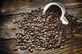 Coffee beans are poured from a Cup on a wooden background. Roasted coffee beans. Royalty Free Stock Photo