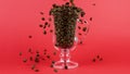 Coffee beans quickly pour, latte glass cup, red background. Refreshing concept