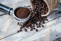 Coffee beans in sack and portafilter on old white wooden table Royalty Free Stock Photo