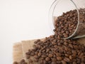 Coffee beans are scattered from a jar on a white table and a canvas napkin Royalty Free Stock Photo