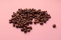 Coffee beans scattered on a pastel background, tinted pink, side view, close-up, space for text