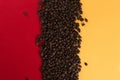 Coffee beans are scattered on a red and yellow paper background close-up, concept, commercial copy space Royalty Free Stock Photo