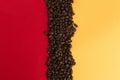 Coffee beans are scattered on a red and yellow paper background close-up, concept, commercial copy space Royalty Free Stock Photo