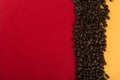 Coffee beans are scattered on a red and yellow paper background close-up, concept, commercial copy space Royalty Free Stock Photo