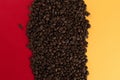 Coffee beans are scattered on a red and yellow paper background close-up, concept, commercial copy space Royalty Free Stock Photo