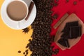 Coffee beans are scattered on a red and yellow paper background and a white cup, cinnamon, star anise, chocolate, concept, Royalty Free Stock Photo