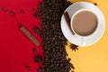 Coffee beans are scattered on a red and yellow paper background and a white cup, cinnamon, star anise, concept, commercial copy Royalty Free Stock Photo