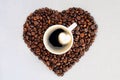 Coffee beans in the shape of a heart and a cup of freshly brewed coffee. Background from coffee Valentine`s Day. Royalty Free Stock Photo