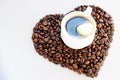 Coffee beans in the shape of a heart and a cup of freshly brewed coffee. Background from coffee Valentine`s Day. Royalty Free Stock Photo