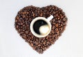 Coffee beans in the shape of a heart and a cup of freshly brewed coffee. Background from coffee Valentine`s Day. Royalty Free Stock Photo