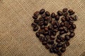 Coffee beans in the shape of a heart on a napkin of natural burlap background. Royalty Free Stock Photo