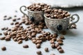 Coffee beans in silver vintage cups on wooden background