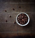 Coffee beans in a small ceramic dish. Rustic wooden background Royalty Free Stock Photo