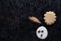 Coffee beans in spilled milk and brown sugar together with a cookie on a black background with silver lining.