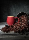 Coffee beans spilled out of a tin can onto a wooden table. Near the burgundy cup and freshly ground coffee. Photo in dark style Royalty Free Stock Photo