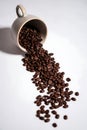 coffee beans spilling from a ceramic mug on a white background Royalty Free Stock Photo