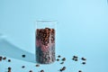Coffee beans spilling out of a cristal jar on mint blue background. Pastel colored wallpaper, trendy fashion photo Royalty Free Stock Photo