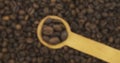 Coffee beans in a spoon. Refocusing from a spoonful of grain to a pile of grain. Rotation.
