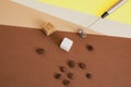 coffee beans, sugar cubes and metal handheld milk steamer on geometric beige and brown background.