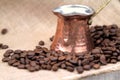 Coffee beans and traditional Turkish copper coffee pot on a burlap