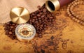 Coffee Beans and Vintage Compass with magnifying glasson an old world map - trade and explorer concept