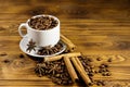 Coffee beans in white cup, cinnamon sticks and star anise on wooden table Royalty Free Stock Photo