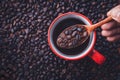 Coffee beans on wooden spoon over a red cup with black coffee Royalty Free Stock Photo