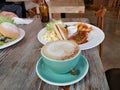 Coffee with Beautiful latte art of cream on top, sandwich, chips/French fries/potato wedge, vegetarian beef at wood table with