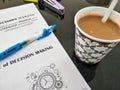 coffee, blue pen, and a book with DECISION MAKING written on it and an explanation in Indonesian. Royalty Free Stock Photo