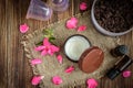 Coffee body scrub, sugar and coconut oil, essential oils, massage vacuum jars on dark wooden rustic table with pink flowers Royalty Free Stock Photo