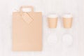 Coffee branding mockup - two brown paper cups with blank bag, label, cap on white wood board, top view. Royalty Free Stock Photo