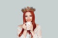 Coffee break of a beauty queen. Portrait of a beautiful woman with long red head hair looking at camera drinking tea, coffee crown Royalty Free Stock Photo