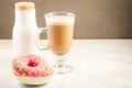 Coffee break: cappuccino, fresh sugary pink donut and white bott